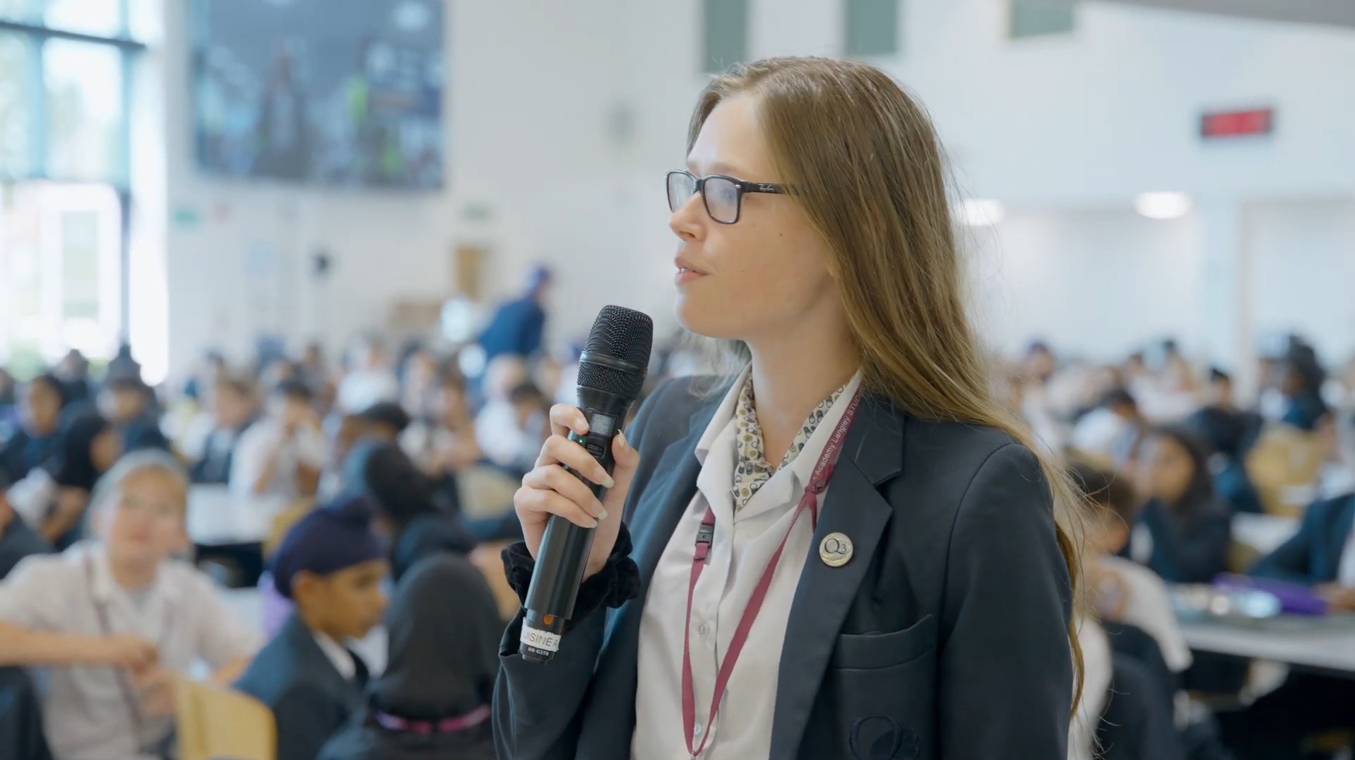 Lucy Hadley speaking on a microphone at a Q3 Langley assembly