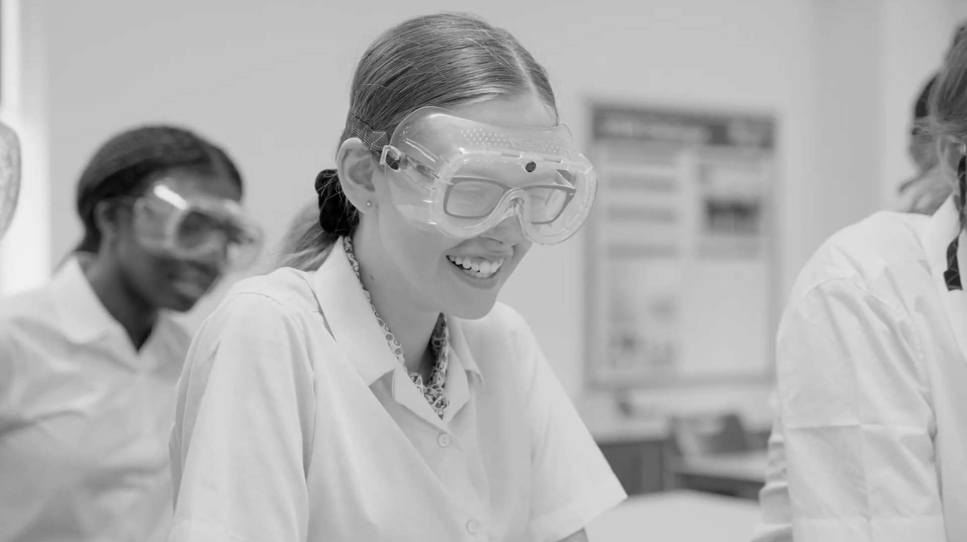 Lucy Hadley working in a science lab, wearing safety goggles and a lab coat